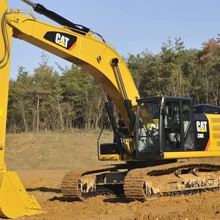 Escavadeira Caterpillar 336E amarela com a marca CAT visível na lateral e no braço, em um terreno de terra com árvores ao fundo.